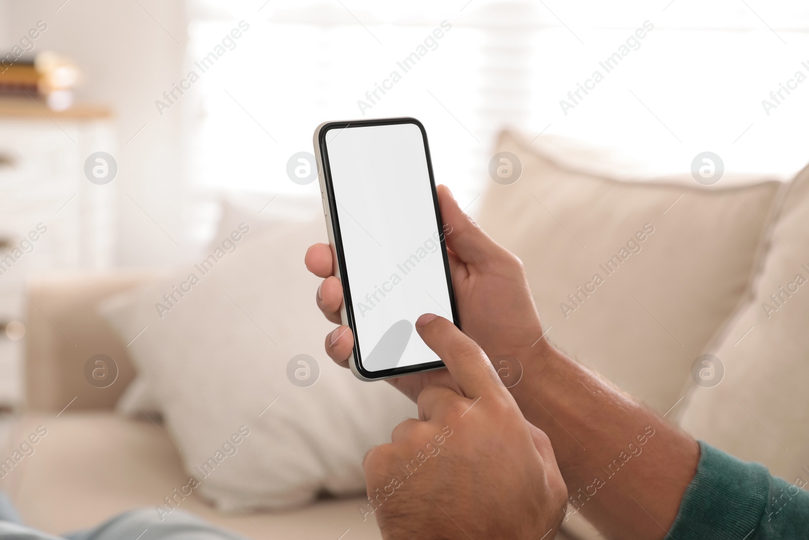 Photo of Man using mobile phone with empty screen indoors, closeup