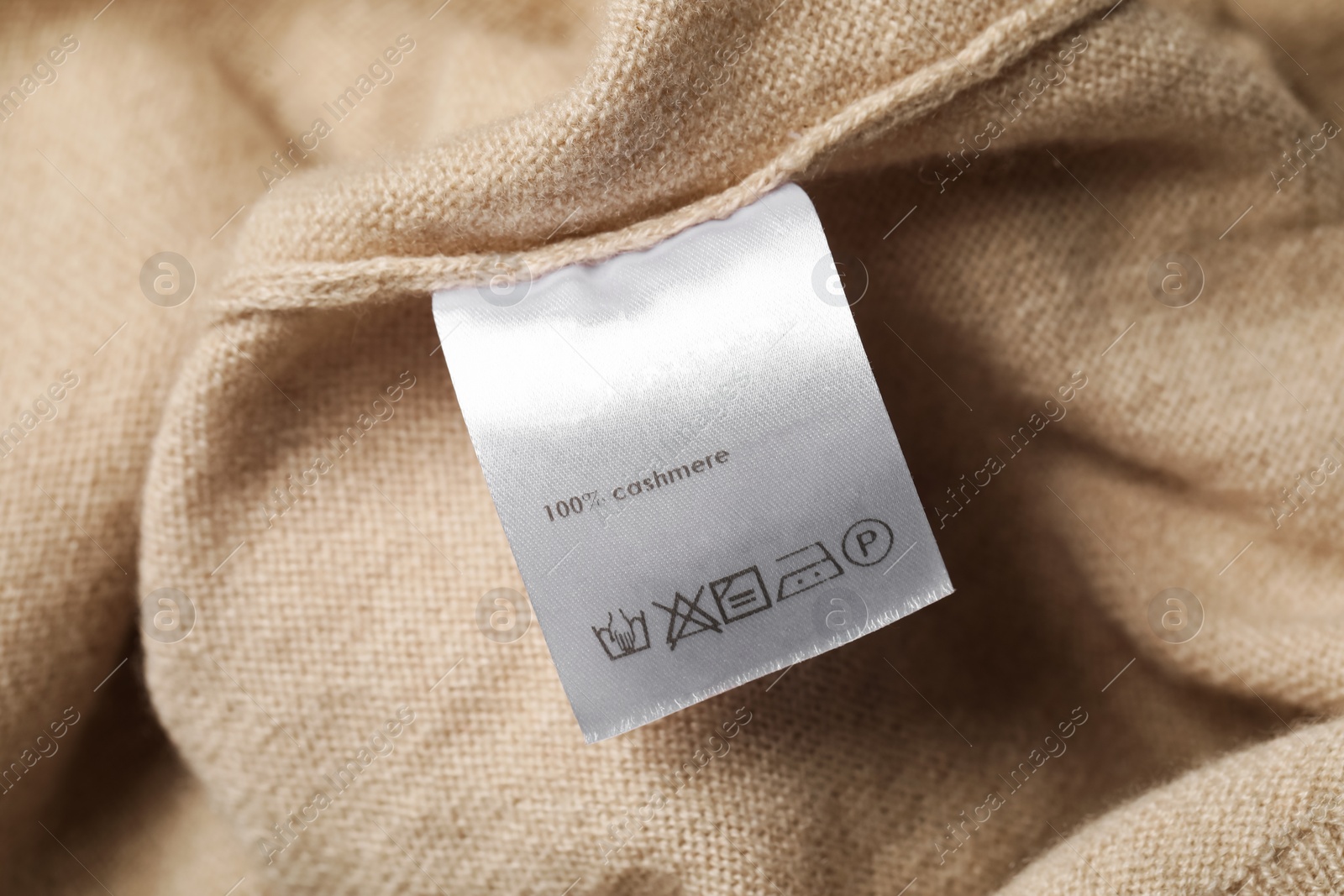 Photo of White clothing label on beige garment, closeup