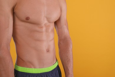 Photo of Shirtless man with slim body on yellow background, closeup. Space for text