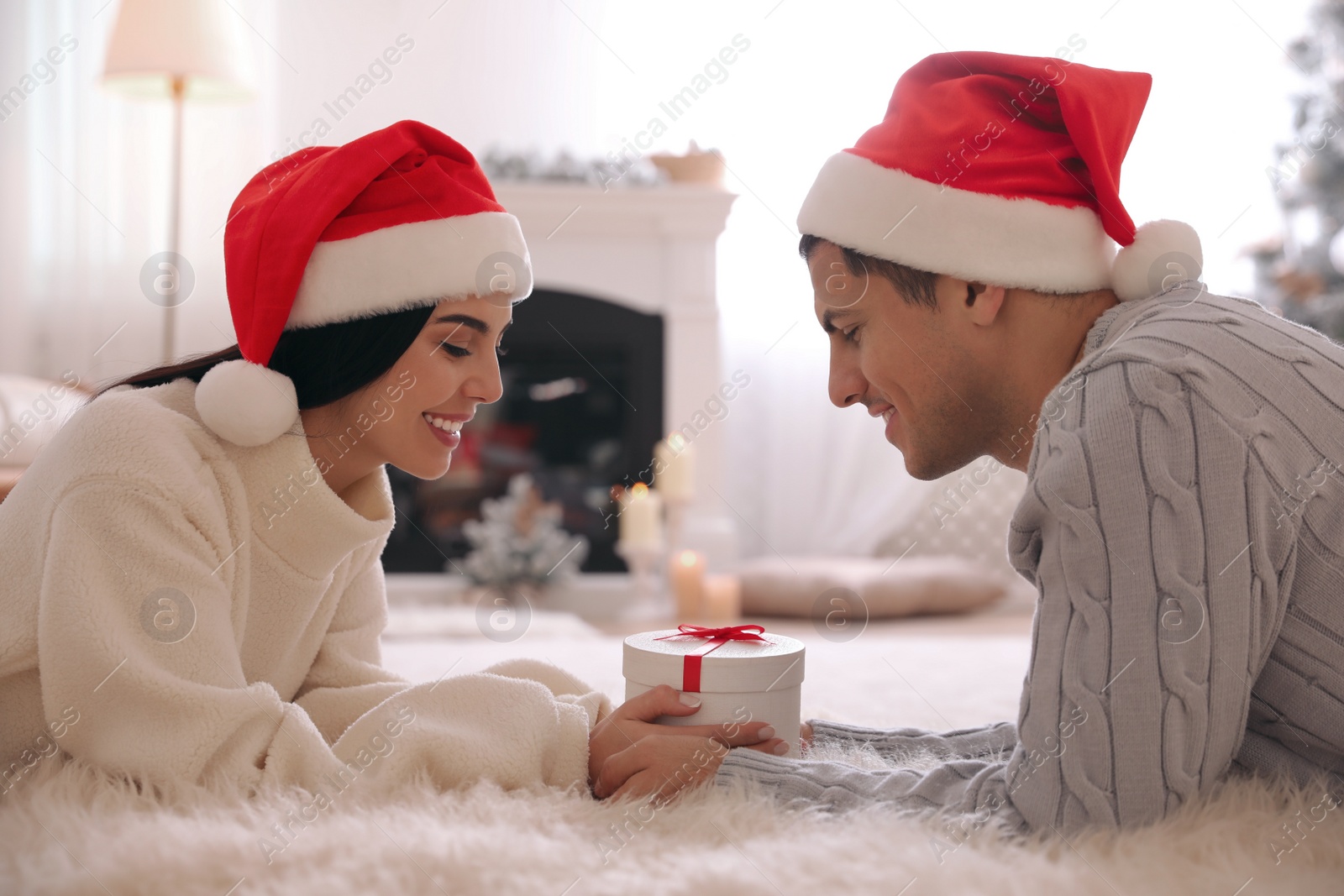 Photo of Couple holding Christmas gift box in living room