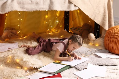 Girl drawing in play tent at home