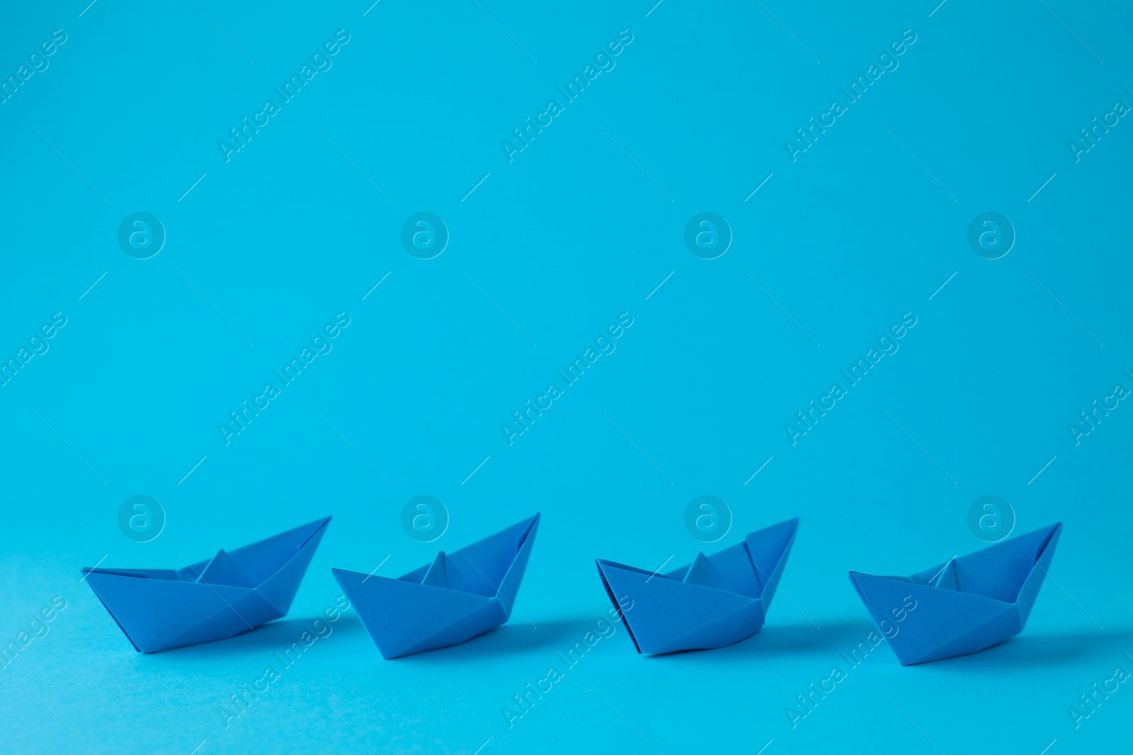 Photo of Handmade paper boats on light blue background. Space for text