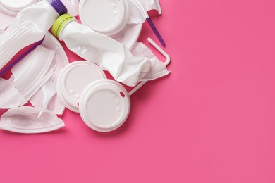 Pile of different plastic items on pink background, flat lay. Space for text