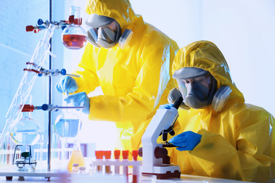 Scientists in chemical protective suits working at laboratory. Virus research