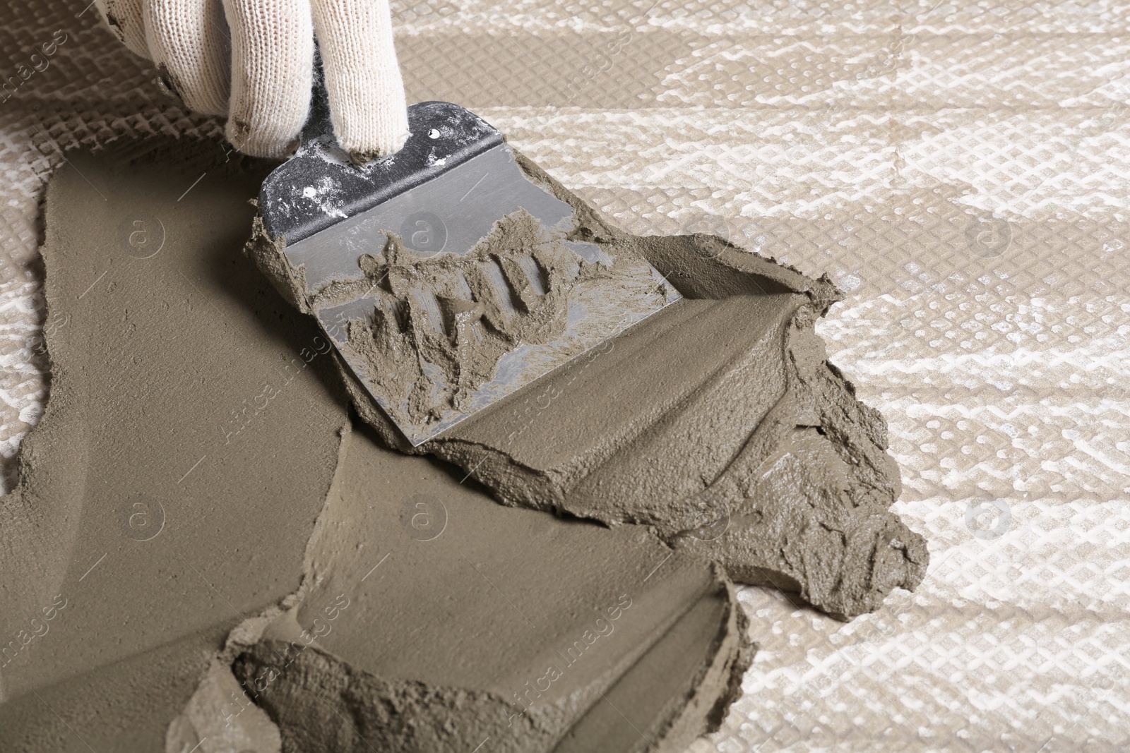 Photo of Worker spreading concrete on ceramic tile with spatula, closeup. Space for text