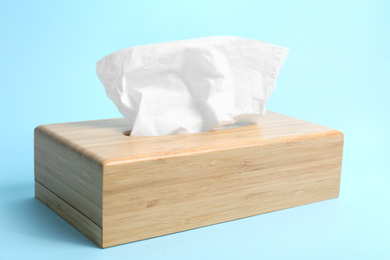 Photo of Holder with paper tissues on light blue background