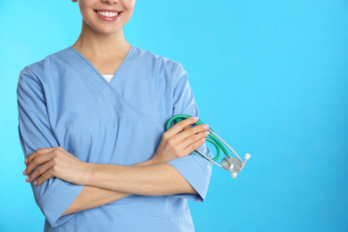 Closeup view of young doctor with stethoscope on blue background, space for text