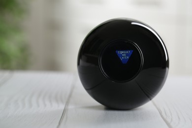 Photo of Magic eight ball with prediction Consult Me Later on light wooden table, closeup. Space for text