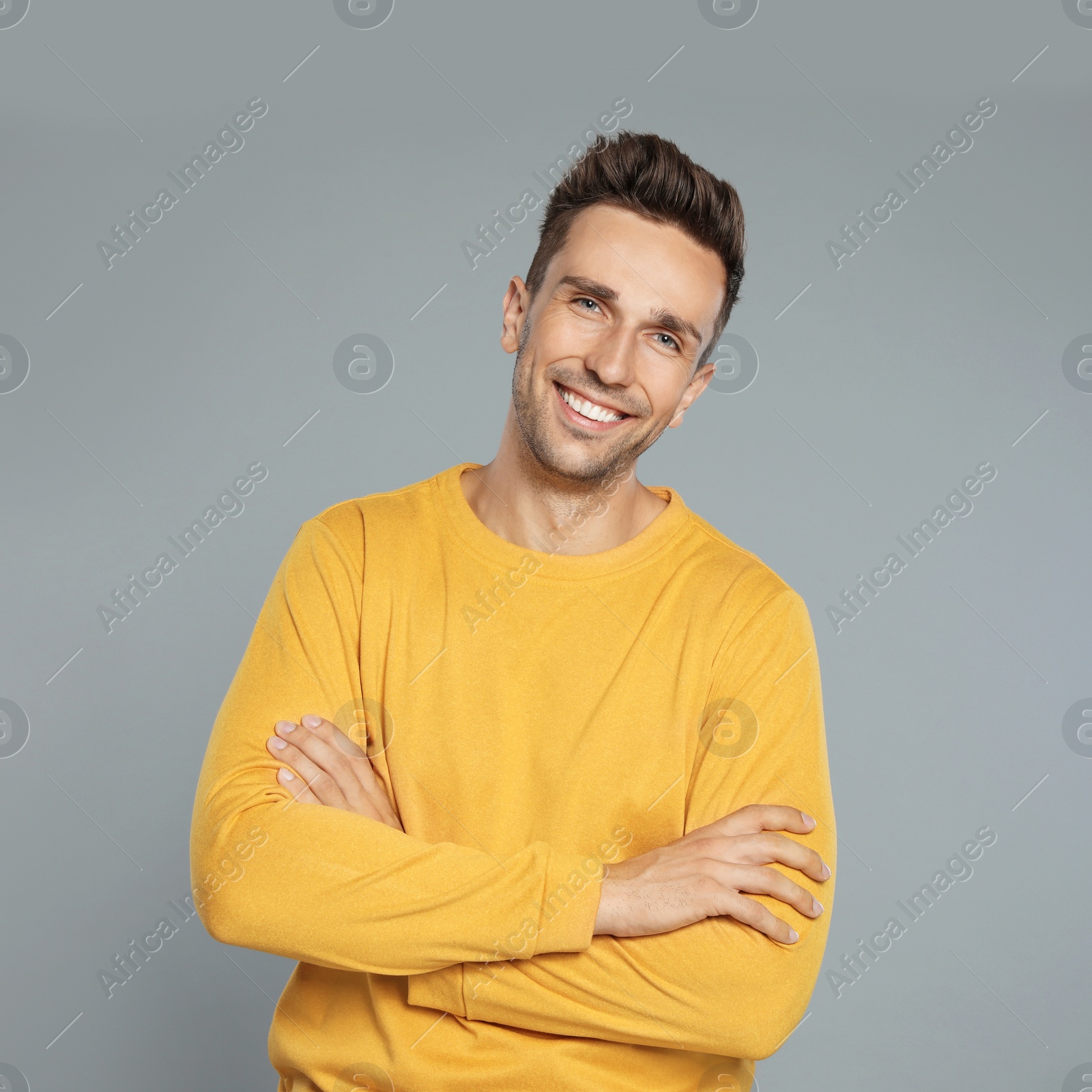 Photo of Happy young man in yellow sweatshirt on grey background. Winter season