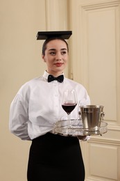Photo of Woman with tray and book on head practicing good posture indoors. Professional butler courses