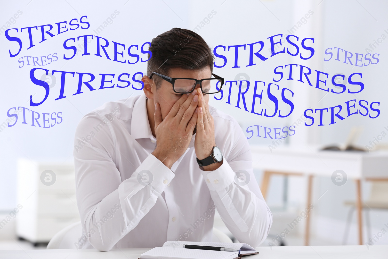 Image of Stressed young man at table in office