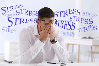 Stressed young man at table in office