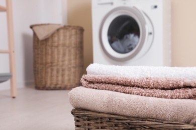 Photo of Basket with laundry and washing machine on background. Space for text