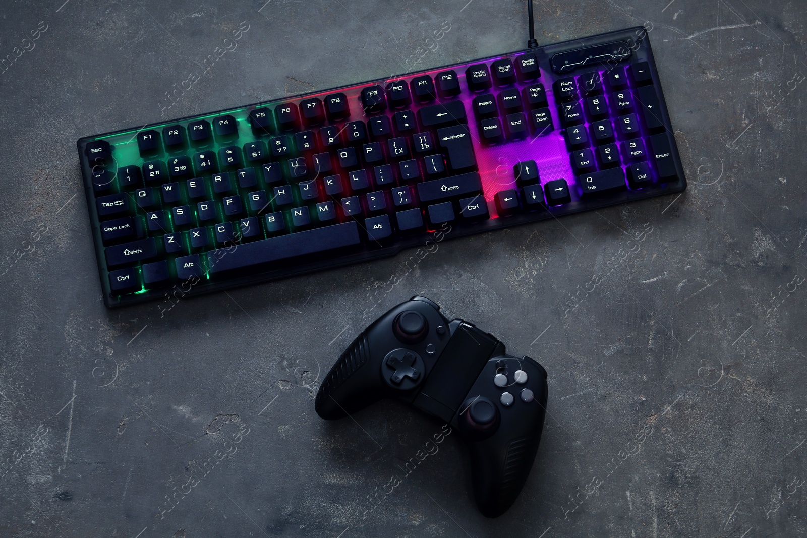 Photo of Modern RGB keyboard and game pad on grey table, flat lay