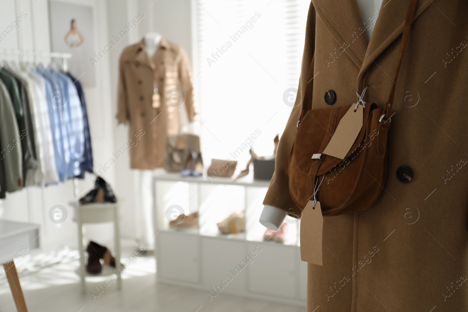 Photo of Stylish woman's clothes, shoes, accessories in modern boutique, focus on mannequin with coat and bag