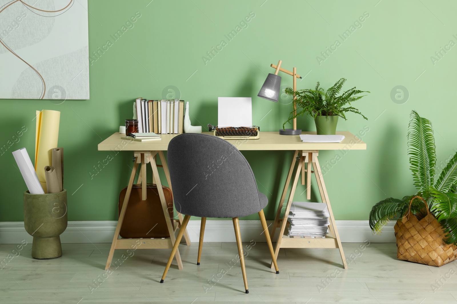 Photo of Writer's workplace with typewriter on wooden desk near pale green wall in room