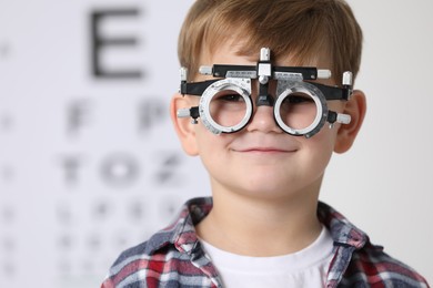 Photo of Little boy with trial frame against vision test chart