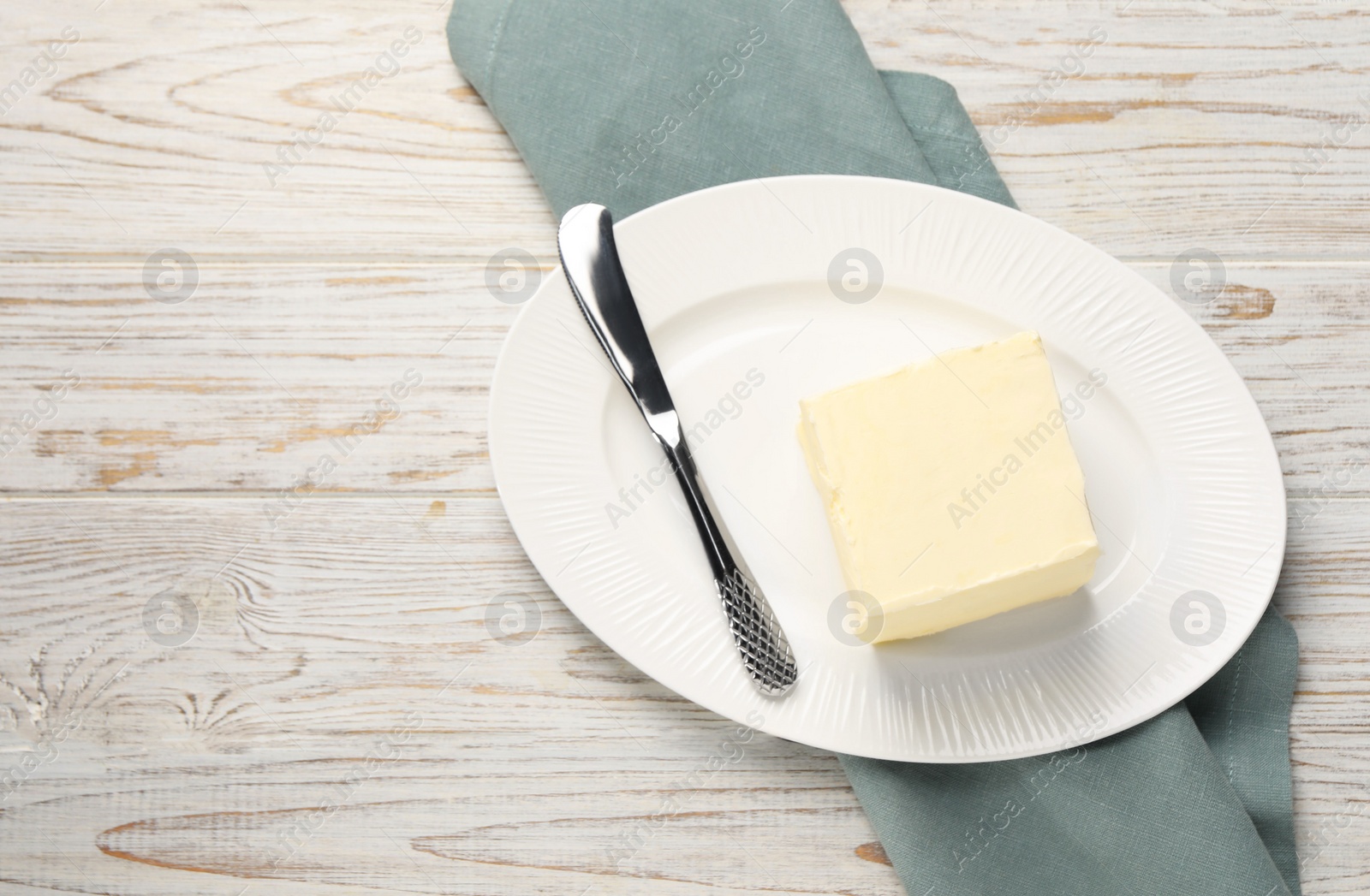 Photo of Block of tasty butter and knife on white wooden table. Space for text