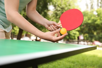 Photo of Young woman playing ping pong in park, closeup