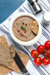 Photo of Tasty liver pate, crispy crackers and tomatoes on blue table, flat lay