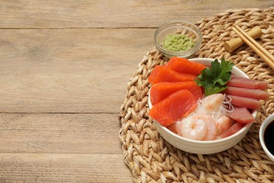 Delicious sashimi set of salmon, shrimps and tuna served with funchosa, parsley, wasabi on wooden table, space for text