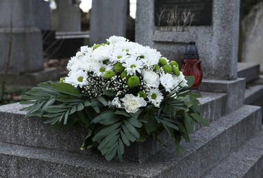 Photo of Funeral wreath of flowers on granite tombstone in cemetery