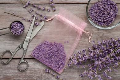 Scented sachet with dried lavender flowers and scissors on wooden table, flat lay