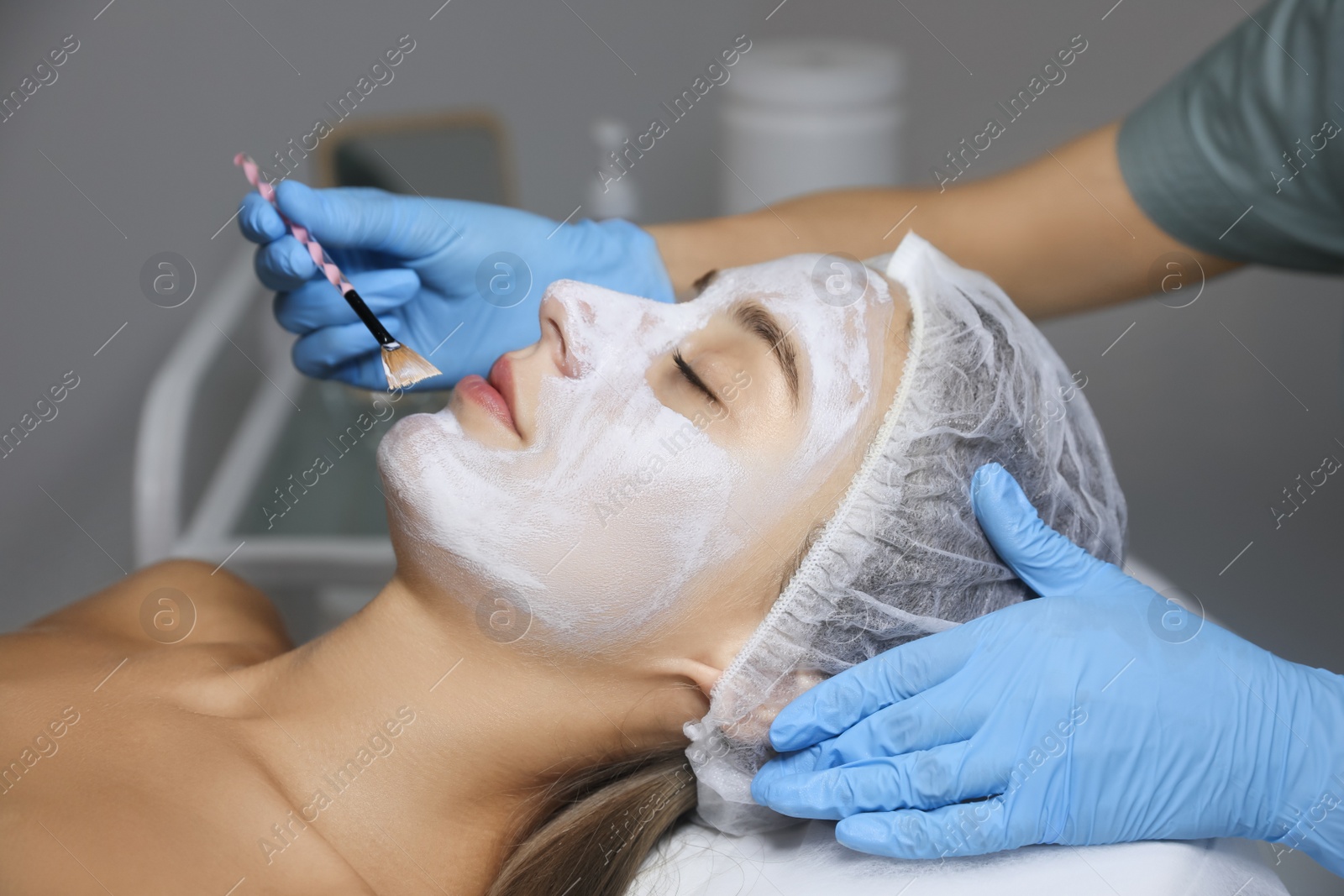 Photo of Cosmetologist applying mask on client's face in spa salon