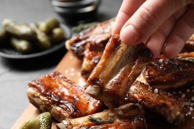 Photo of Woman with tasty grilled ribs at table, closeup