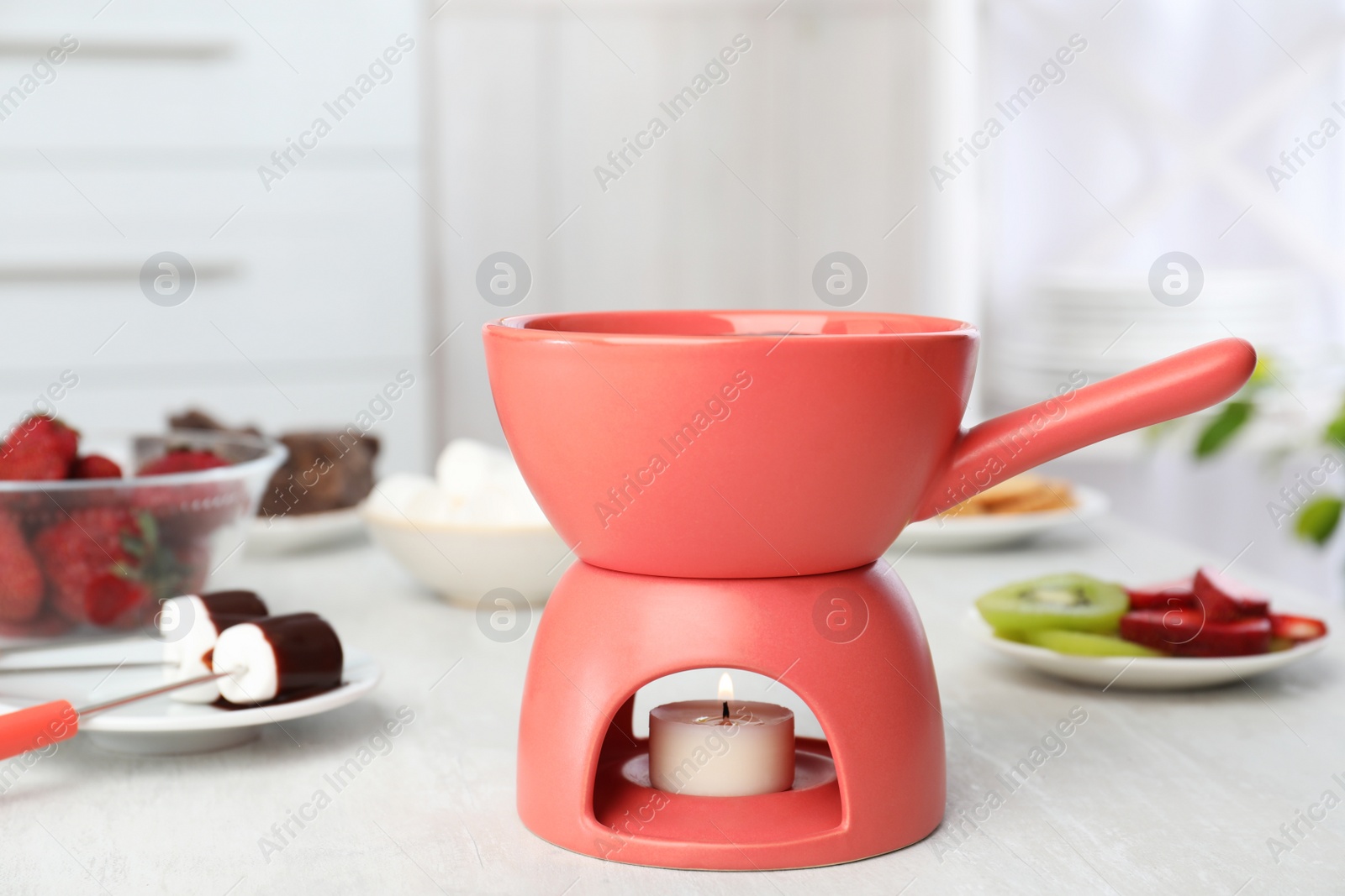 Photo of Ceramic fondue pot with candle on table