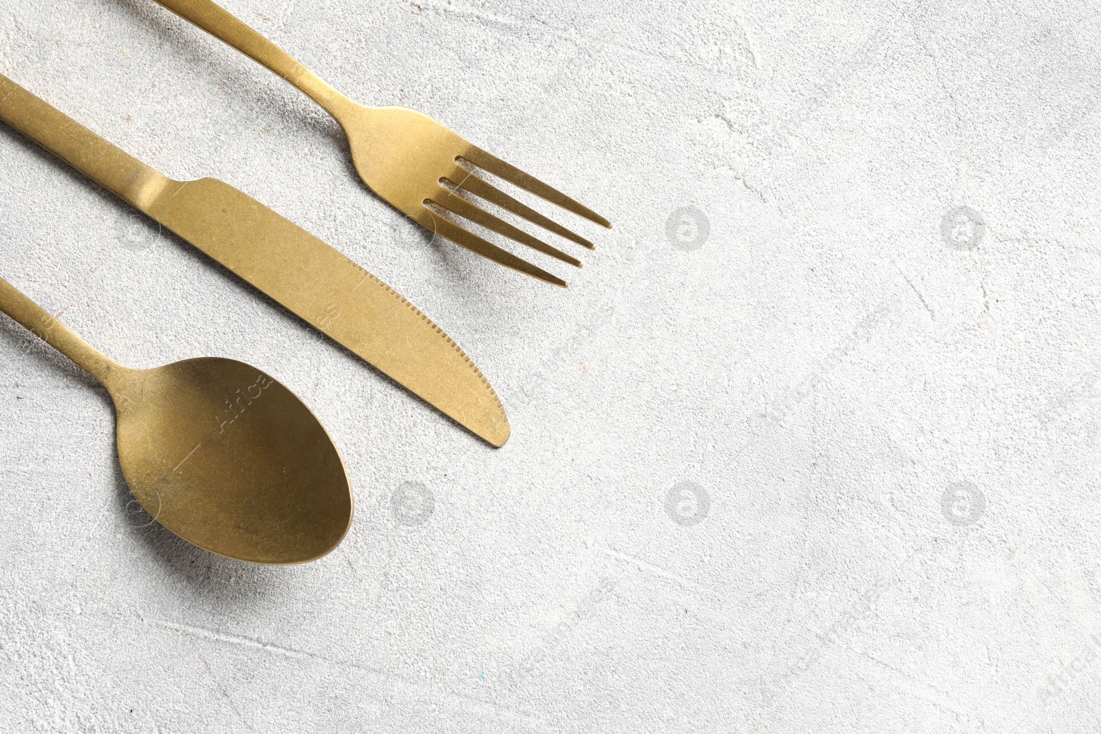 Photo of Stylish cutlery on light grey table, above view. Space for text