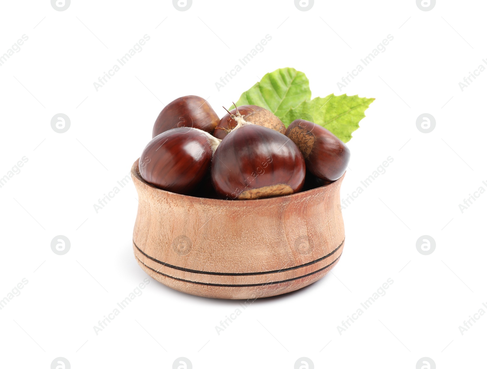 Photo of Fresh sweet edible chestnuts with green leaves in wooden bowl on white background