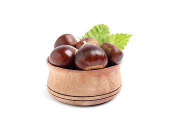 Photo of Fresh sweet edible chestnuts with green leaves in wooden bowl on white background