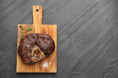 Piece of delicious grilled beef meat, thyme and salt on black table, top view. Space for text