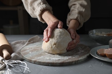 Photo of Woman kneading dough at grey table, closeup