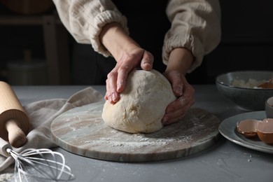 Woman kneading dough at grey table, closeup