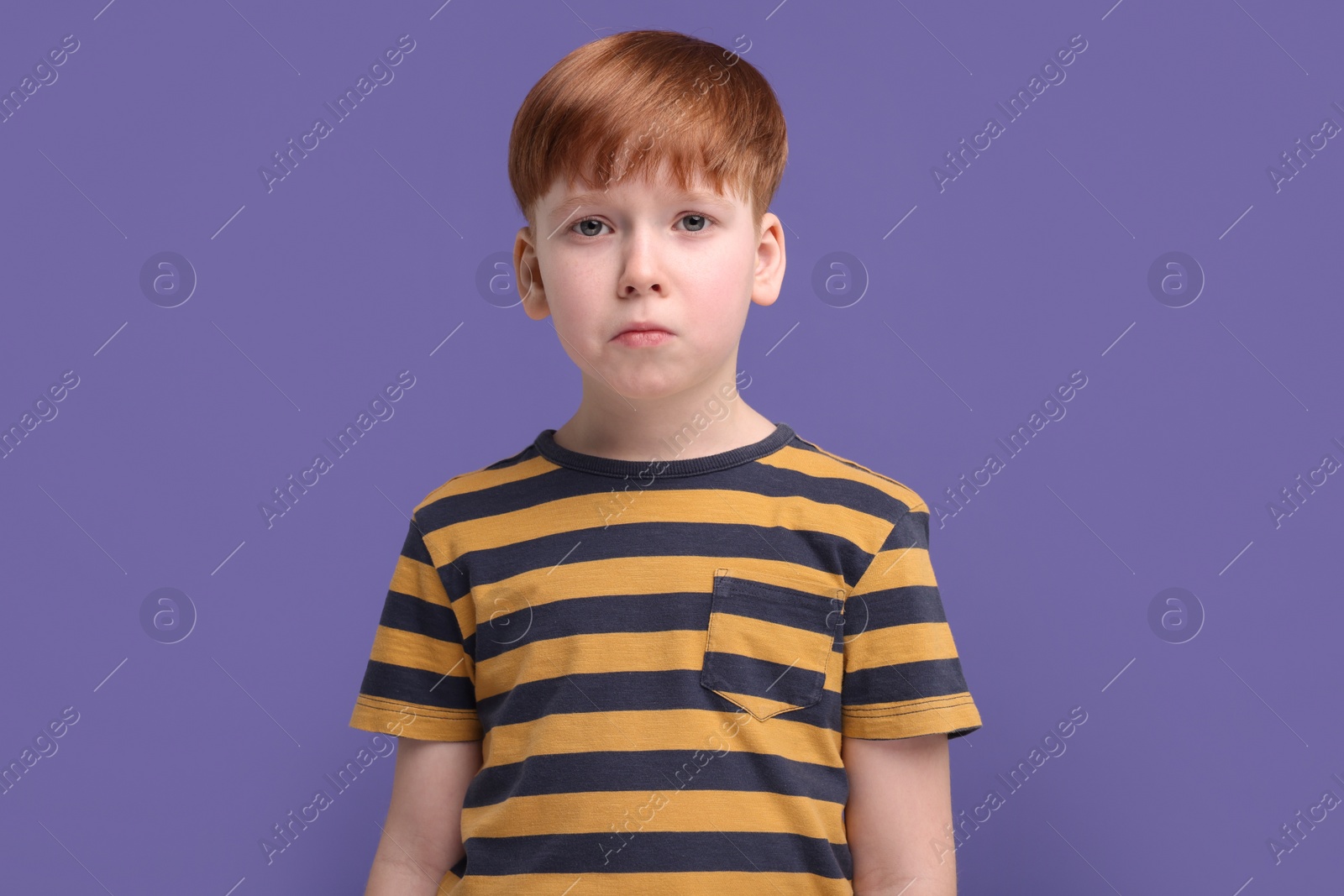 Photo of Portrait of sad little boy on purple background