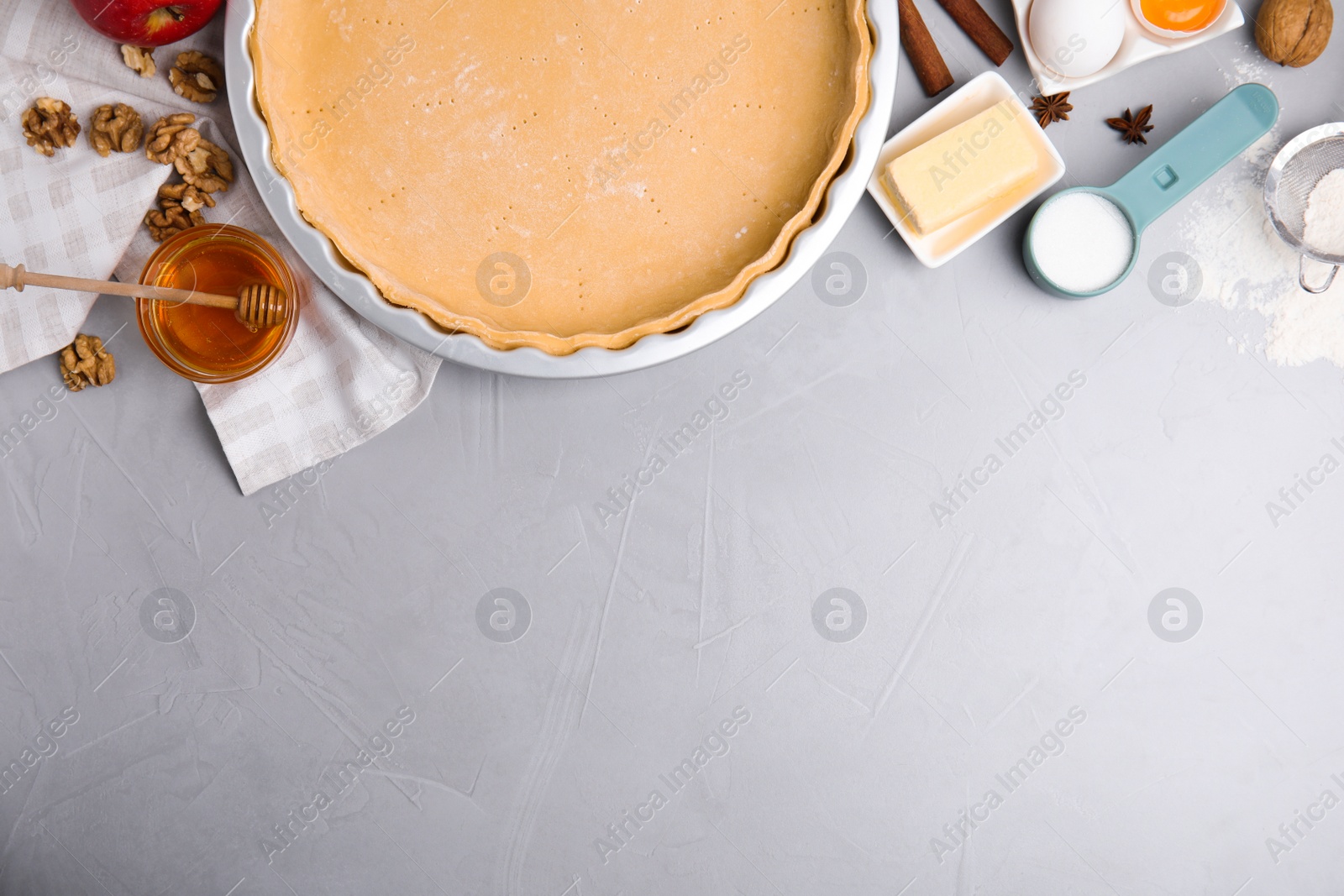 Photo of Raw dough and traditional English apple pie ingredients on light grey table, flat lay. Space for text