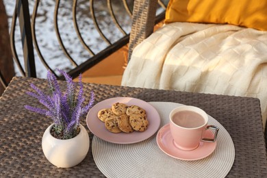 Photo of Cup with tasty cocoa and cookies on rattan table at balcony