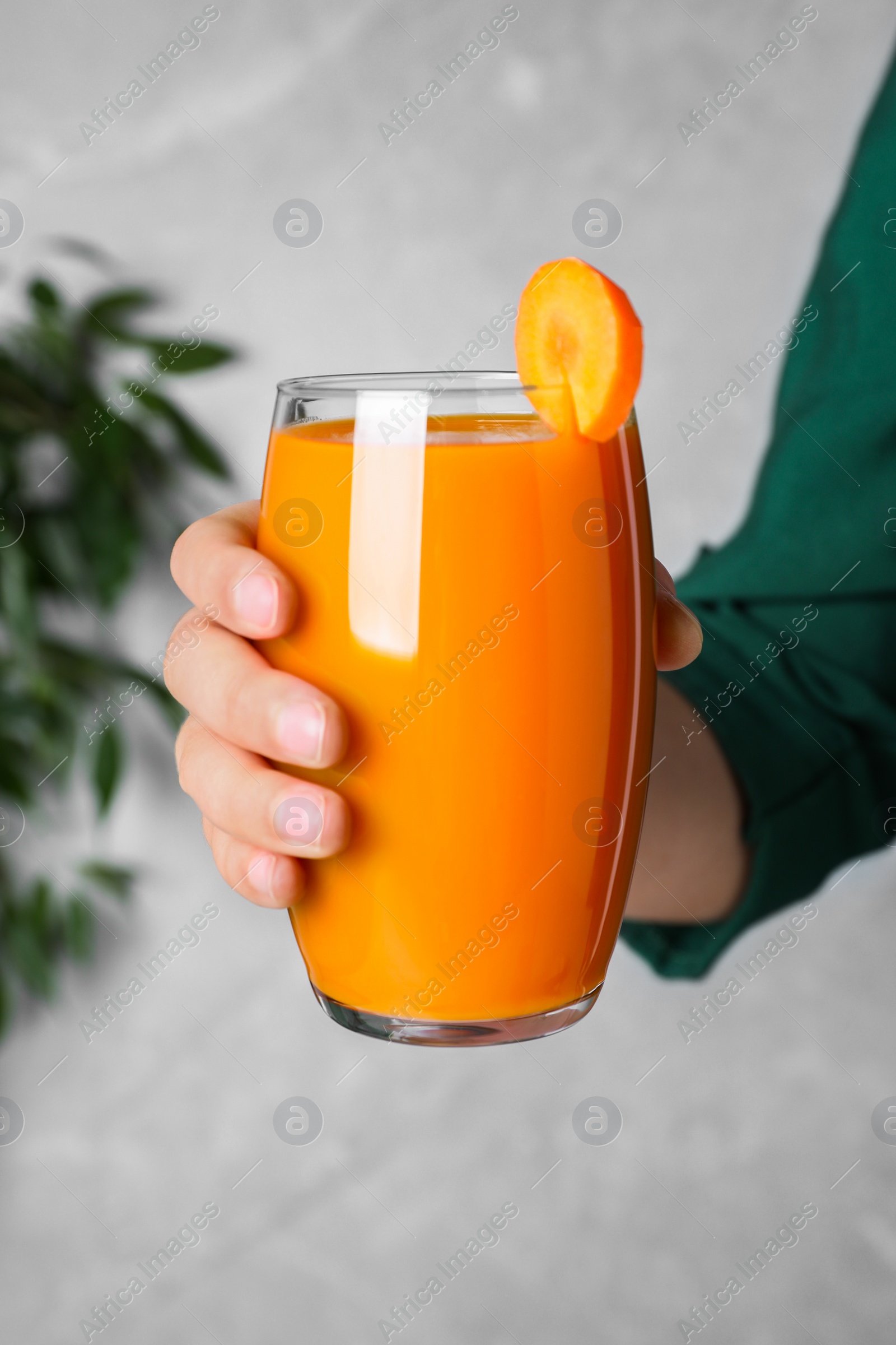 Photo of Woman holding glass with carrot juice, closeup