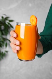 Photo of Woman holding glass with carrot juice, closeup