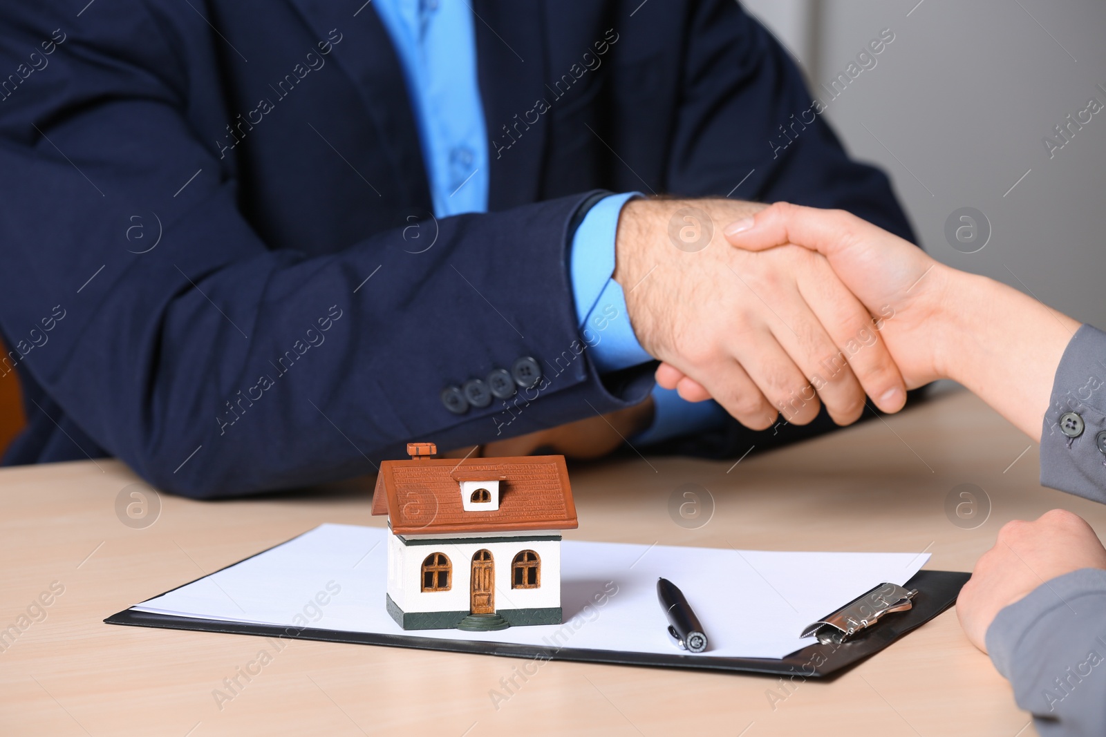 Photo of Woman shaking hands with real estate agent at table in office, closeup. Home insurance