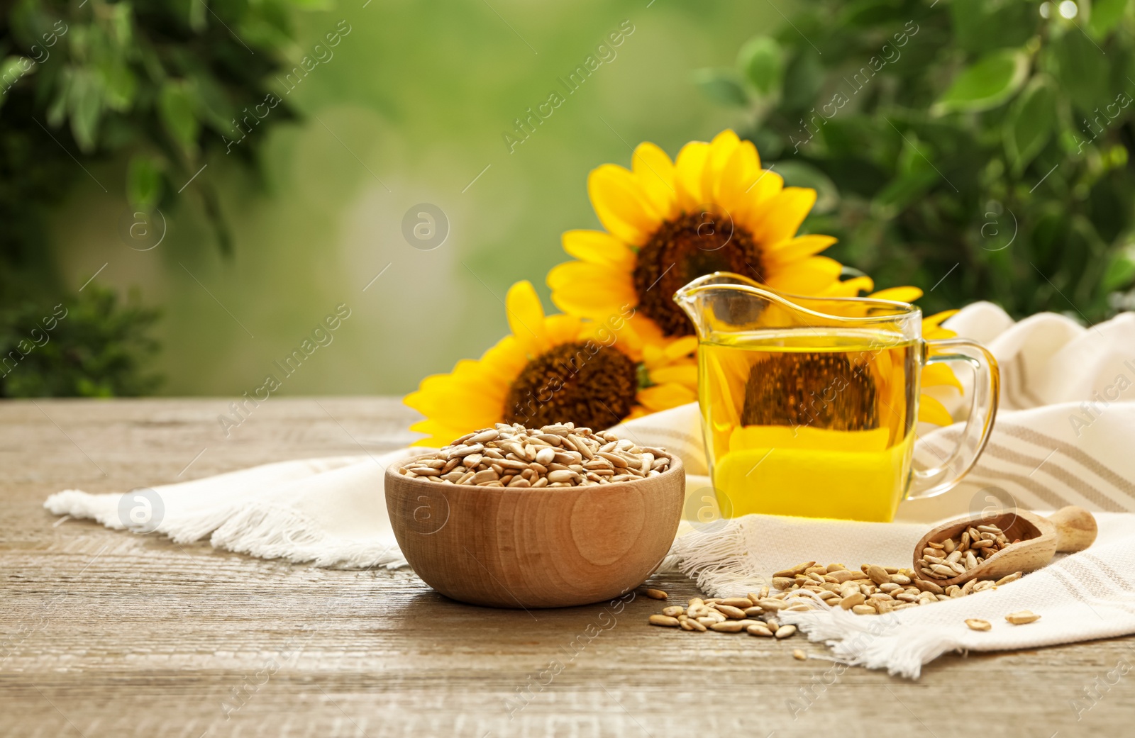 Photo of Sunflower oil and seeds on wooden table against blurred background, space for text