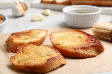 Photo of Slices of delicious toasted bread with garlic on table, closeup