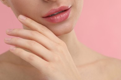 Photo of Young woman with beautiful full lips on pink background, closeup