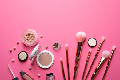 Flat lay composition with makeup brushes on pink background. Space for text