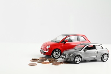 Toy cars and money on white background, space for text. Vehicle insurance