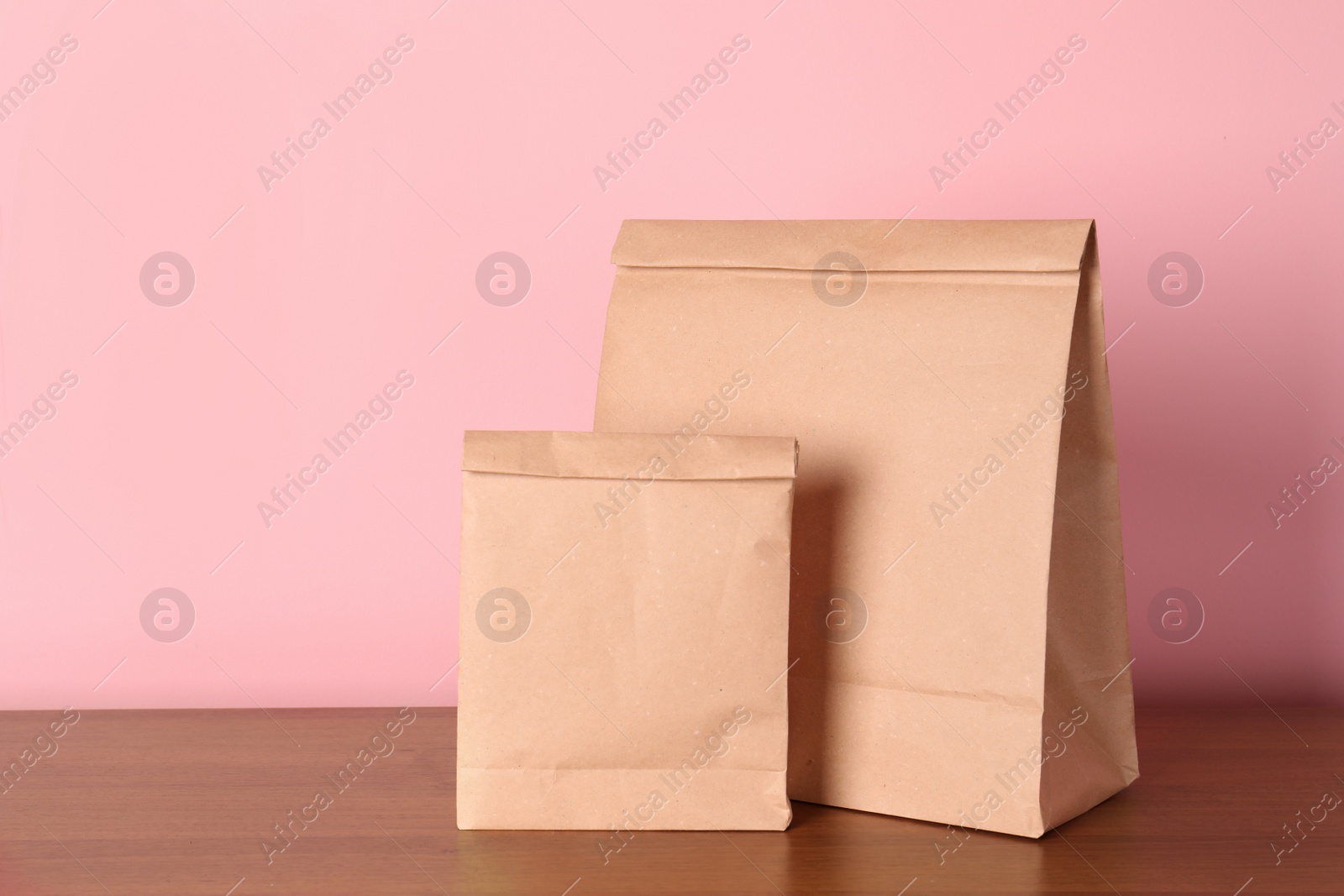 Photo of Paper bags on table against color background. Mockup for design