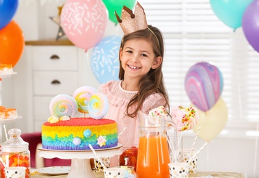 Happy girl at table with treats in room decorated for birthday party