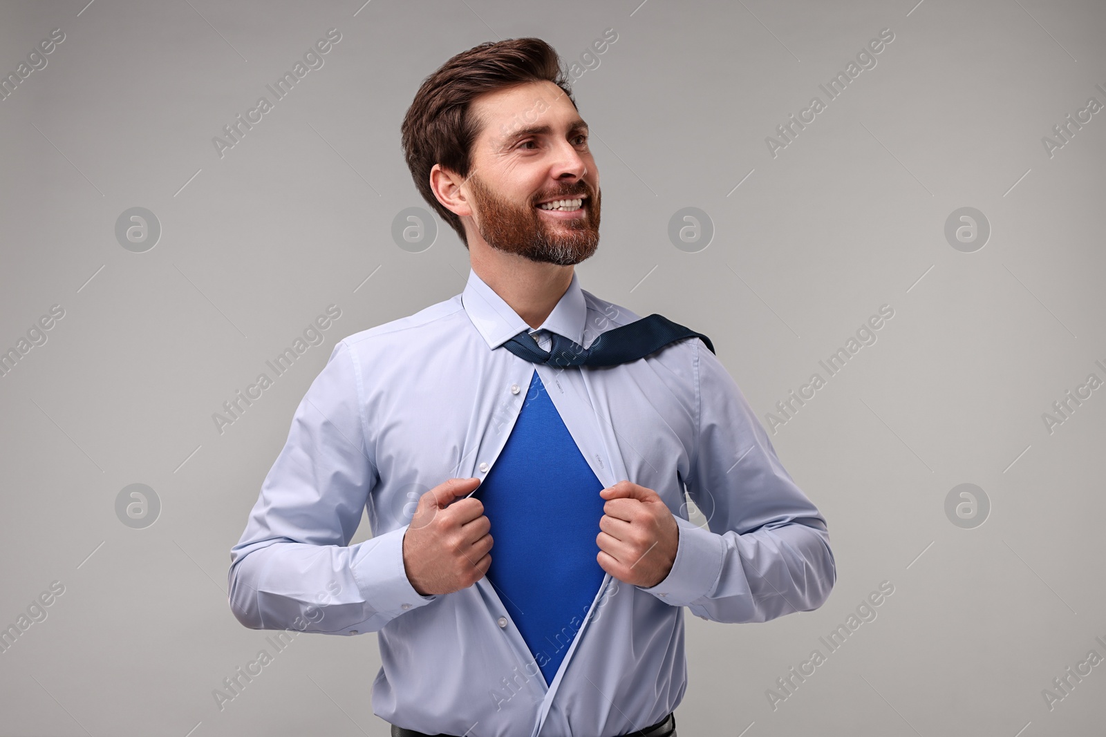 Photo of Happy businessman wearing superhero costume under suit on beige background